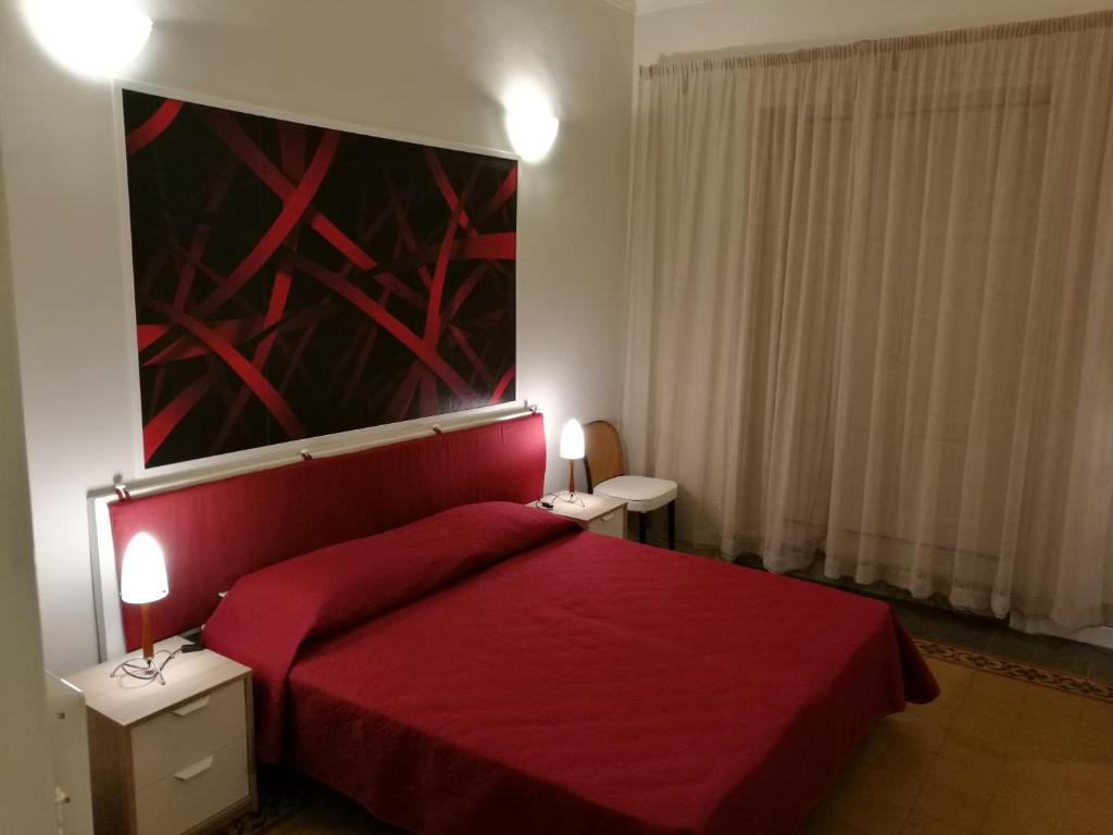 a bedroom with a red bed and a painting on the wall at Ursino rooms apartment in Catania