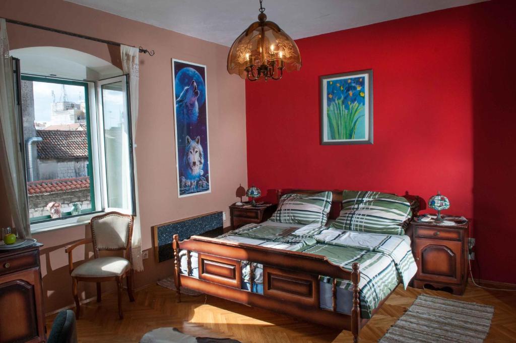- une chambre dotée d'un mur rouge avec un lit et un lustre dans l'établissement Buga And Tuga Rooms, à Split