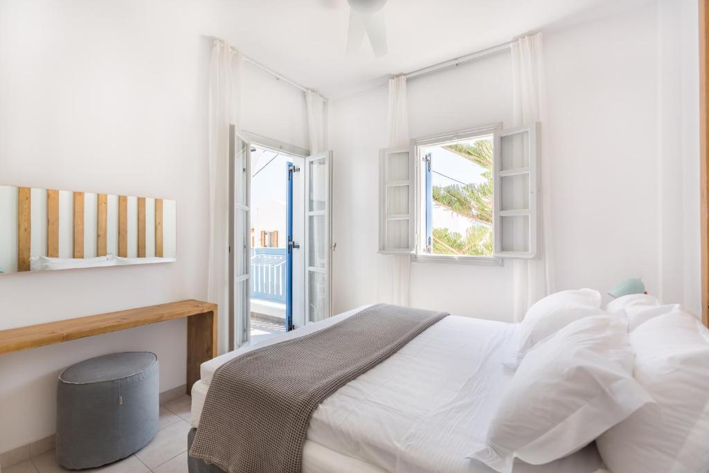 a white bedroom with a bed and two windows at Fanouris Condo - Adults Only in Kamari
