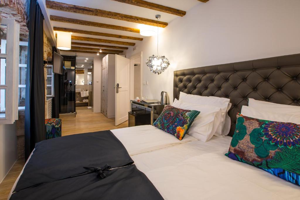 a bedroom with a large bed with a black headboard at Spalato Luxury Rooms in Split