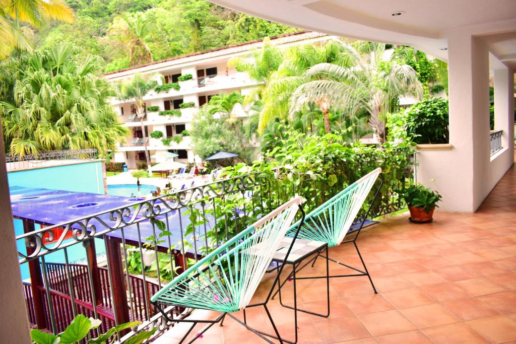 a balcony with chairs and a table and a building at Hotel Casa Iguana Mismaloya in Puerto Vallarta