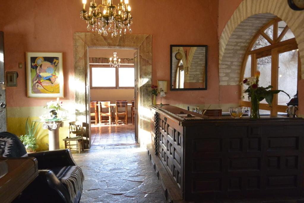 a living room with a chandelier and a kitchen with a counter at Hotel Amor y Paz in Real de Catorce