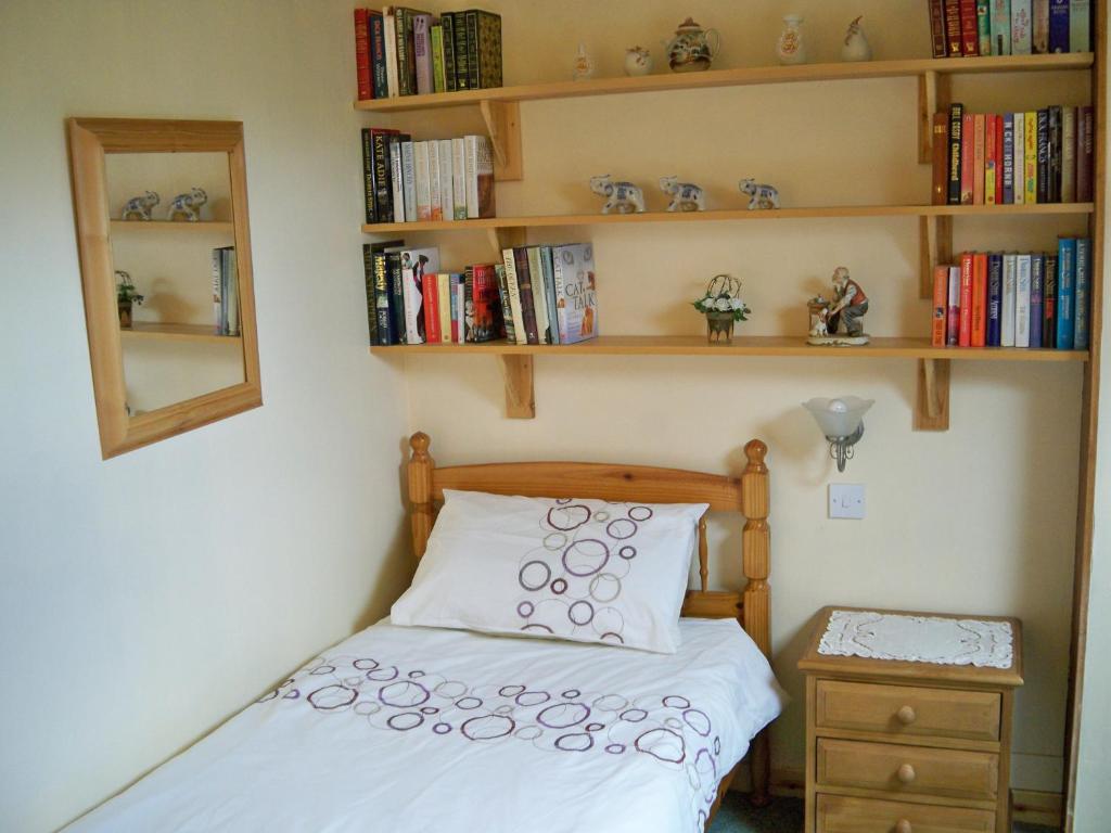 a bedroom with a bed and shelves with books at Tamara Apartment in Sandwick