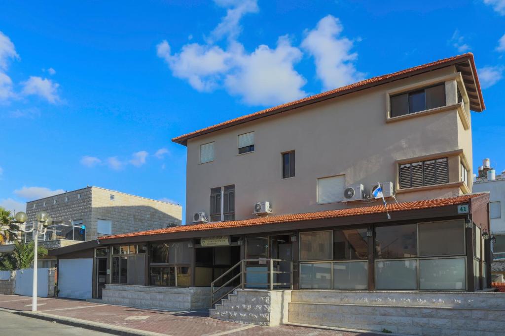 ein Gebäude auf einer Straße mit blauem Himmel in der Unterkunft Amigo Hotel On The Beach in Naharija