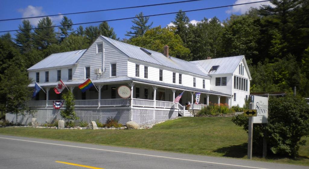 a white house with flags on the front of it at The Sterling Inn in Caratunk