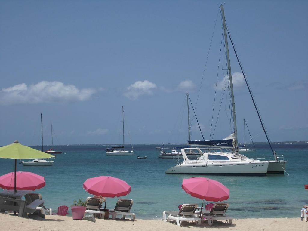 馬里戈的住宿－Studio Chic Saint-Martin，海滩上的一组椅子和遮阳伞,有船