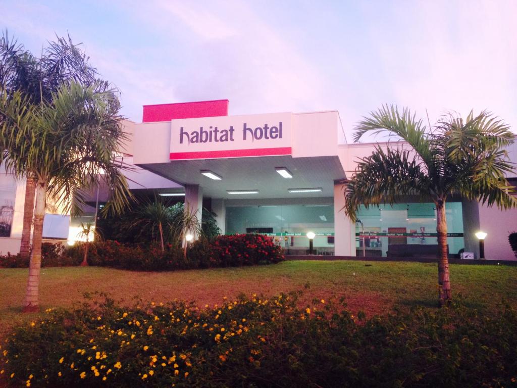 a hotel with palm trees in front of a building at Habitat Hotel Pirassununga in Pirassununga