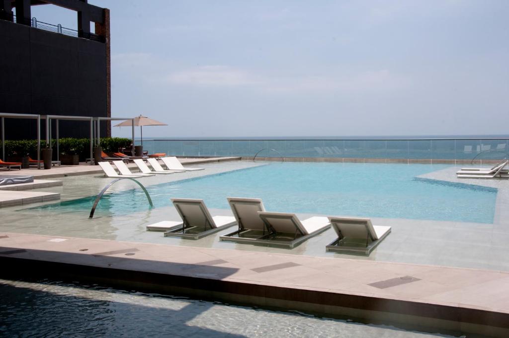 a swimming pool with lounge chairs in a building at Apartamentos Morros City Cartagena in Cartagena de Indias