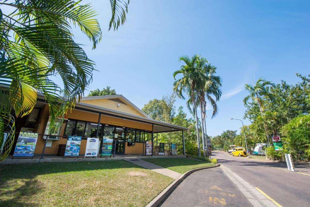 a building on the side of a street with palm trees at Hidden Valley Holiday Park Darwin in Darwin