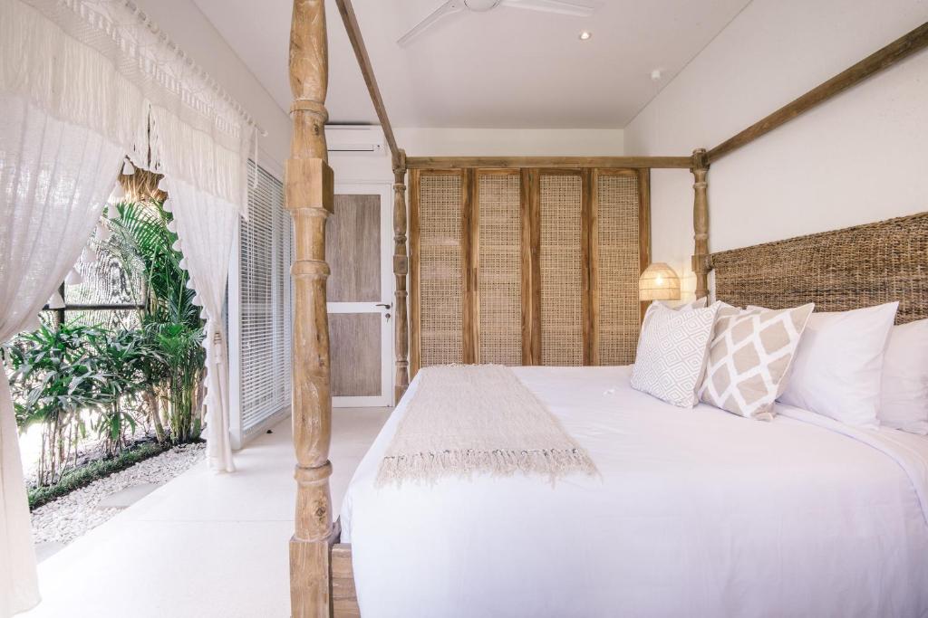 a bedroom with a four poster bed and a window at Villa Santai at Sandy Bay in Nusa Lembongan