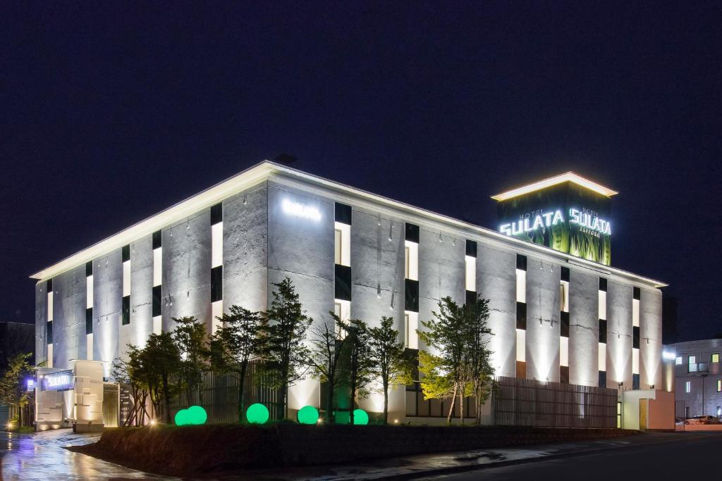 a building with a sign on top of it at night at HOTEL SULATA Sapporo (Adult Only) in Sapporo