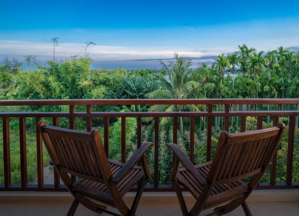 two chairs sitting on a balcony with a view at Riverside Hamlet Homestay & Villa in Hoi An