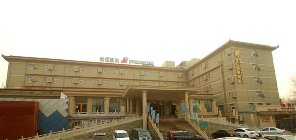 ein großes Gebäude mit Autos auf einem Parkplatz in der Unterkunft Jinjiang Inn Changzhi Bayi Square in Changzhi