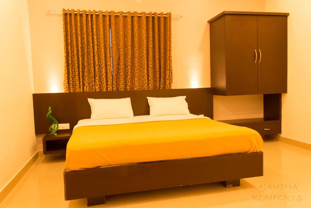 a bedroom with a large bed with a yellow blanket at Ajantha Komforts, Bengaluru in Bangalore