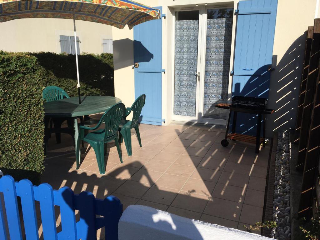 eine Terrasse mit einem Tisch, Stühlen und einem Klavier in der Unterkunft Maison vacances Noirmoutier Barbatre in Barbâtre
