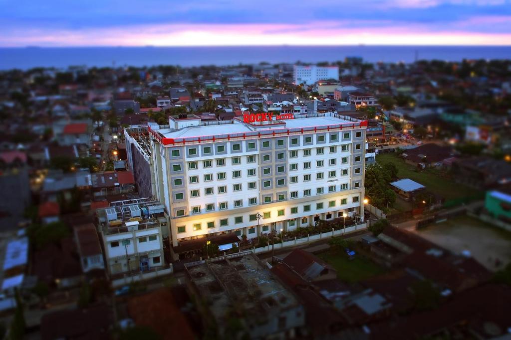 a white building with a red sign on top of it at Rocky Plaza Hotel Padang in Padang