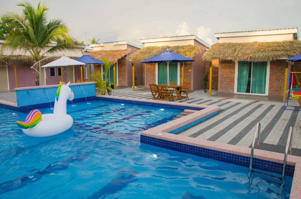 uma piscina com um cisne em frente a uma casa em Lavigo Resort em Pantai Cenang