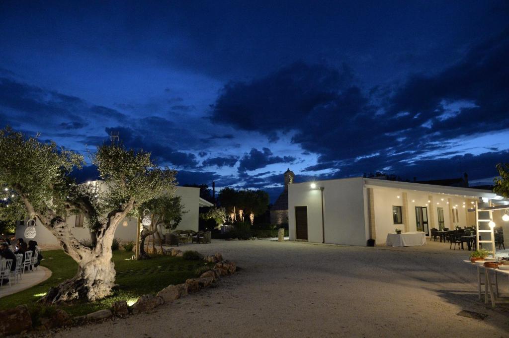 un edificio con un árbol delante de él por la noche en Masseria Corte Masseriola, en Alberobello