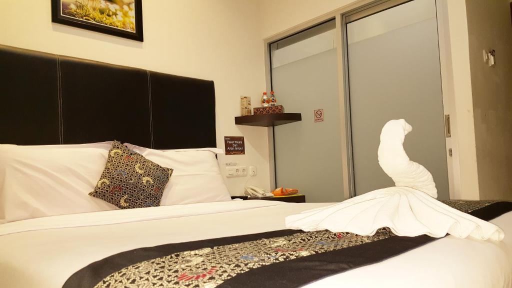 a bedroom with a bed with a white dress on it at Sunrise Hotel Jombor Jogja in Yogyakarta