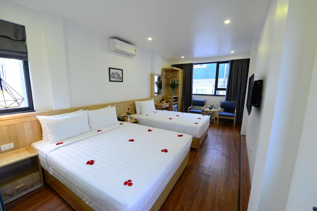 a hotel room with two beds with red flowers on them at Blue Hanoi Inn Luxury Hotel in Hanoi