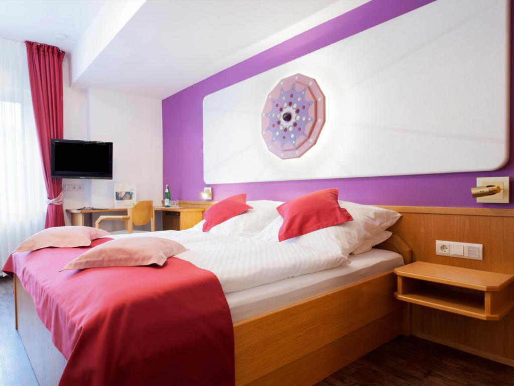 a bedroom with a bed with red and white pillows at Hotel Landgasthof Rüppel in Ramsbeck