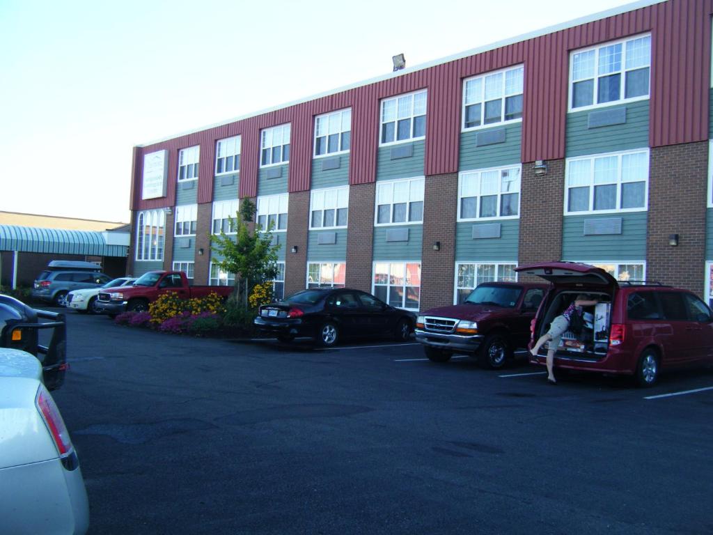 un parking avec des voitures garées devant un bâtiment dans l'établissement Claymore Inn and Suites, à Antigonish