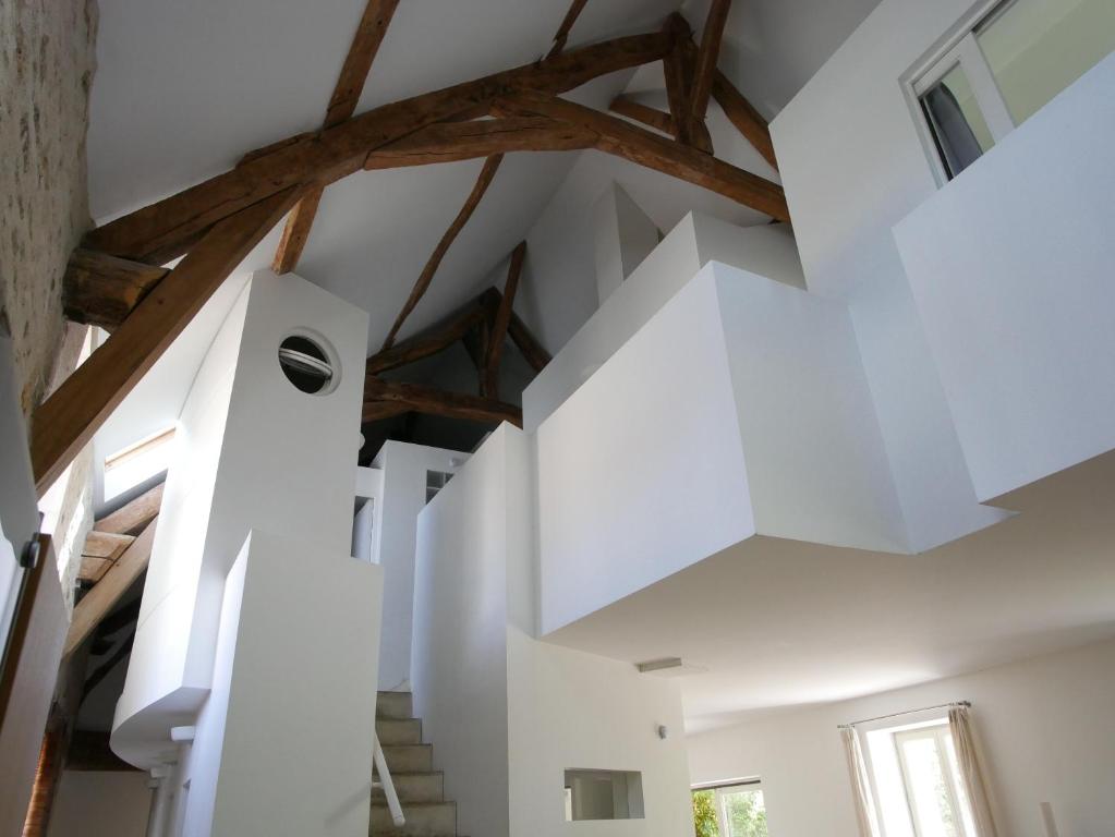 una escalera en una casa con paredes blancas y vigas de madera en Gîtes de la Grande Ferme, en Avernes