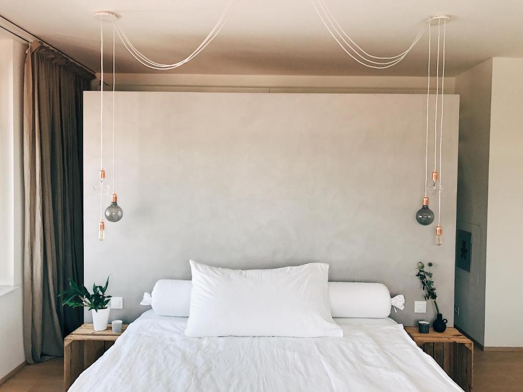 Un dormitorio con una cama blanca con dos lámparas. en AVLiving City LOFT Basel, en Basilea