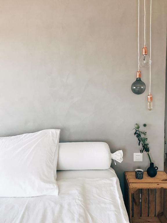 a bedroom with a bed with white sheets and lights at AVLiving City LOFT Basel in Basel