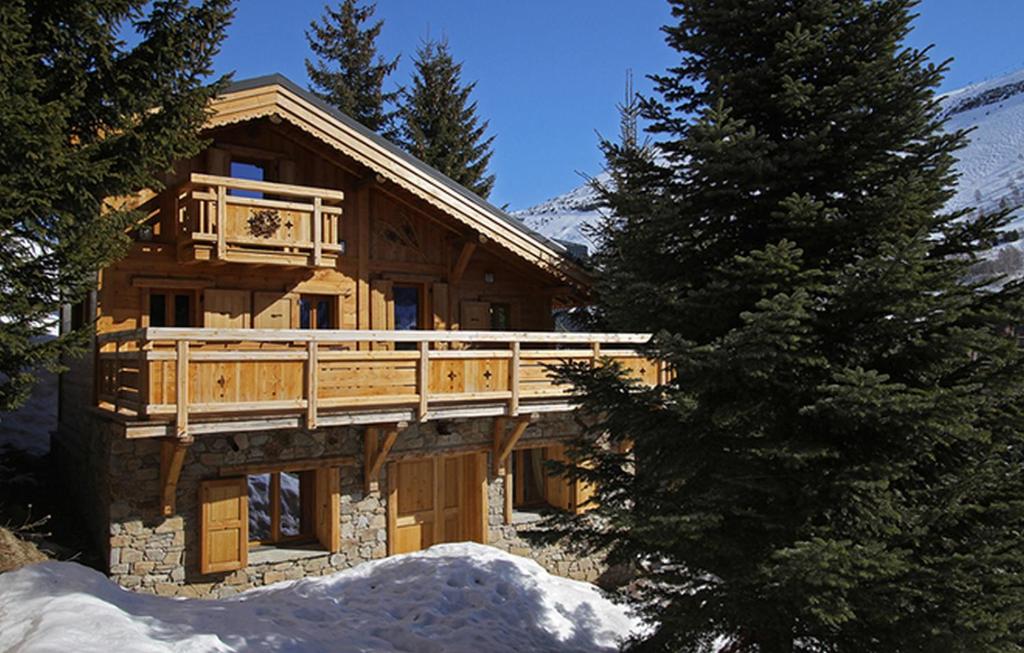 a log cabin with a deck in the snow at Odalys Chalet Les Alpages in Les Deux Alpes