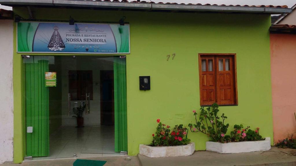 a green building with a door and flowers at Pousada Nossa Senhora Aparecida in Mucugê