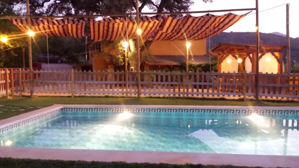 uma piscina à noite com uma cerca de madeira em El Encinar de Cobo em Fuensanta de Martos