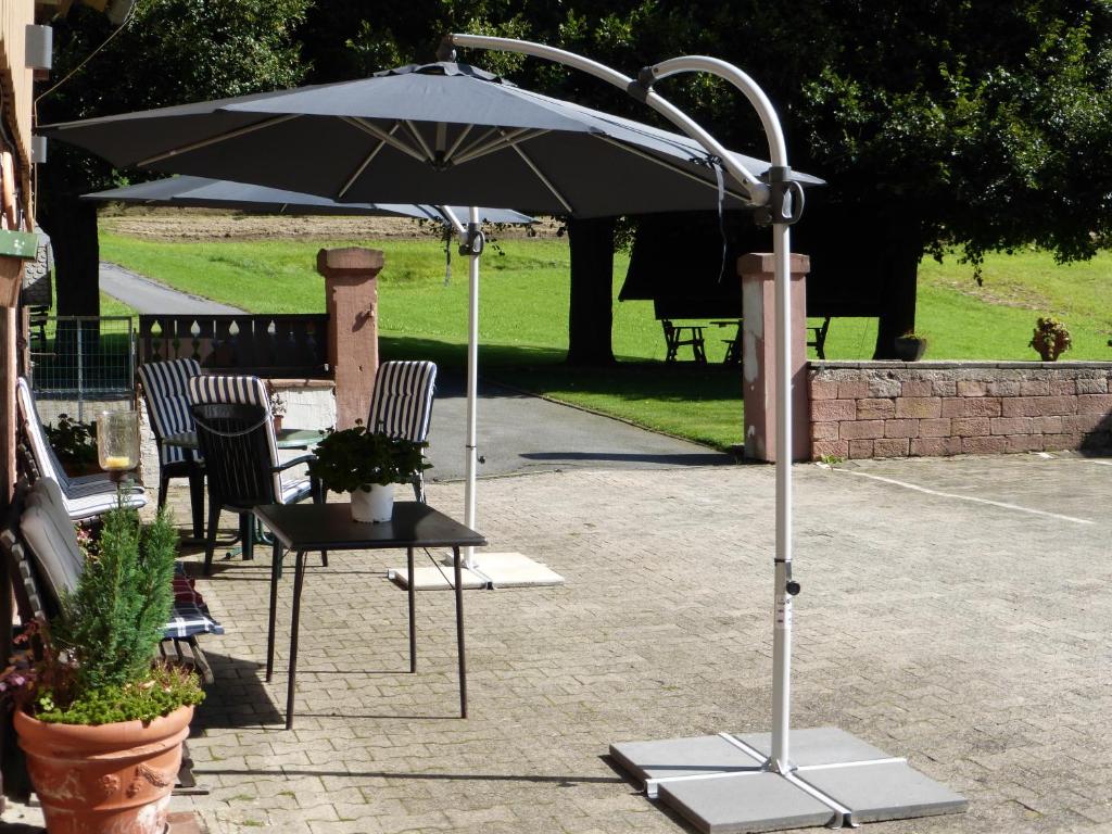 an umbrella and a table with chairs under it at Ferienwohnungen Zur Mühle in Mossautal