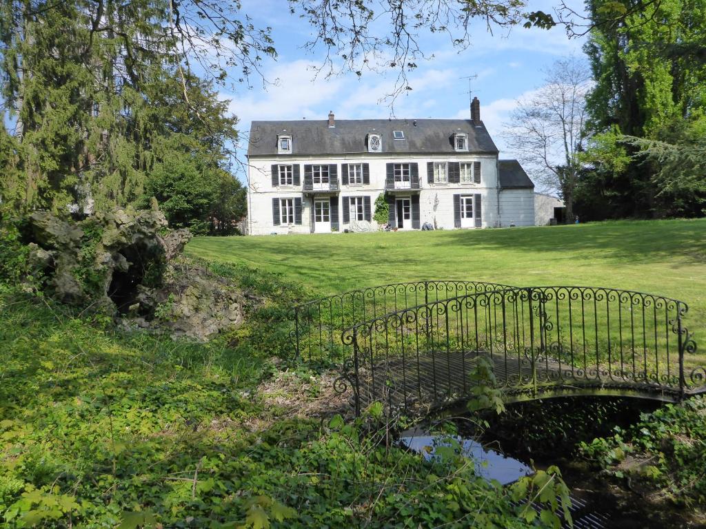 une grande maison blanche avec un pont devant elle dans l'établissement Clairefontaine Chambre d'Hôtes, à Angy