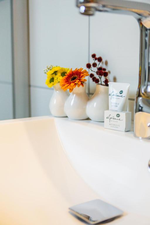 a white counter with flowers in vases on it at Alpen Appartement BelEtage in Mayrhofen