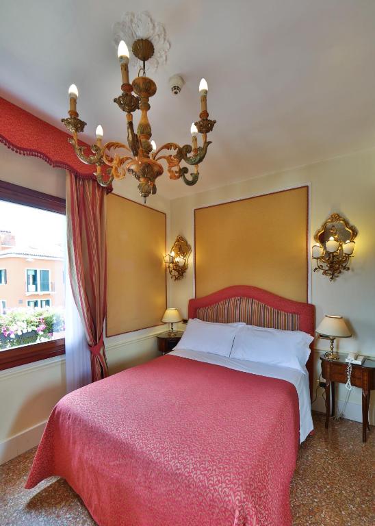 a bedroom with a large bed with a red blanket at Hotel Arlecchino in Venice