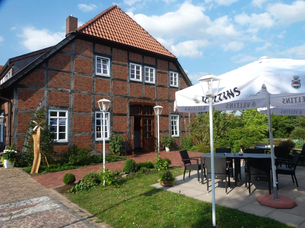 une maison avec une table et un parasol dans l'établissement Mühlengasthof Landesbergen, à Landesbergen