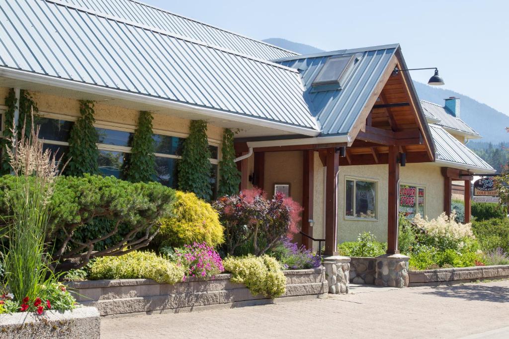 uma casa com um telhado de metal e algumas flores em The Lodge at Arrow Lakes em Nakusp