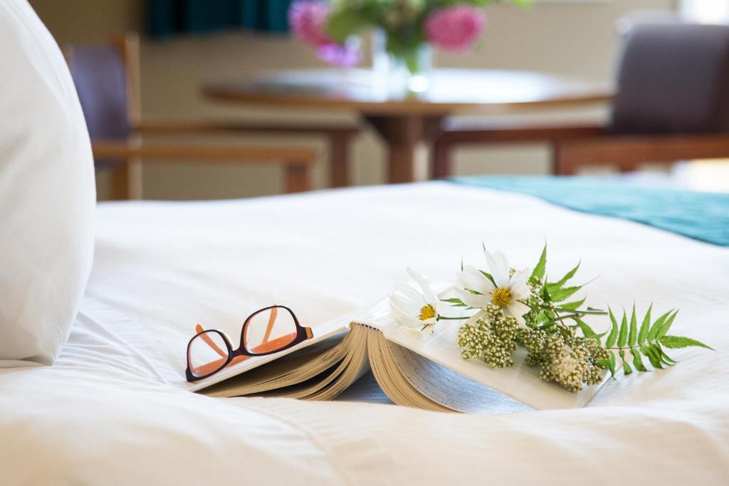 a pair of glasses and a book on a bed at The Lodge at Arrow Lakes in Nakusp