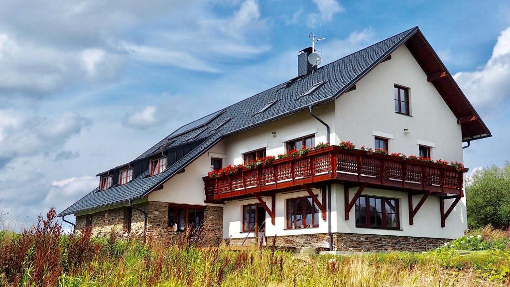 a large white house with a black roof at Apartmány Chajdovka in Boží Dar