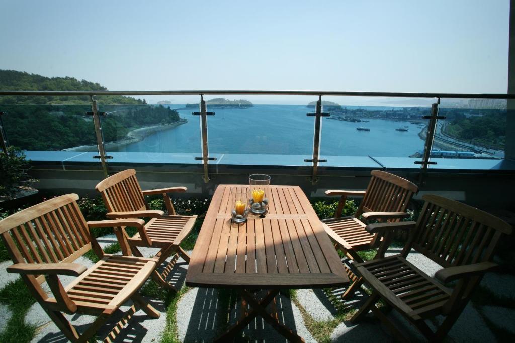 uma mesa e cadeiras de madeira com vista para a água em Benikea Hotel Yeosu em Yeosu