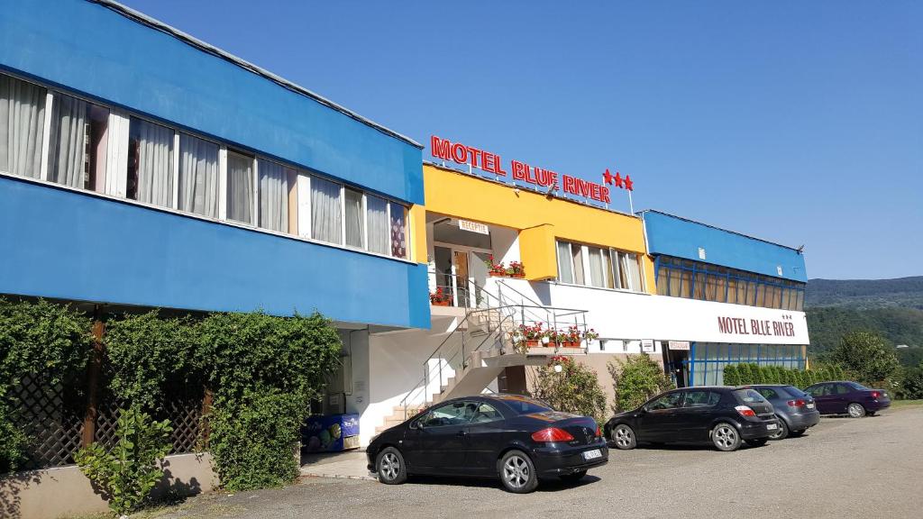 een rij auto's geparkeerd voor een gebouw bij Motel Blue River Calimanesti in Călimăneşti