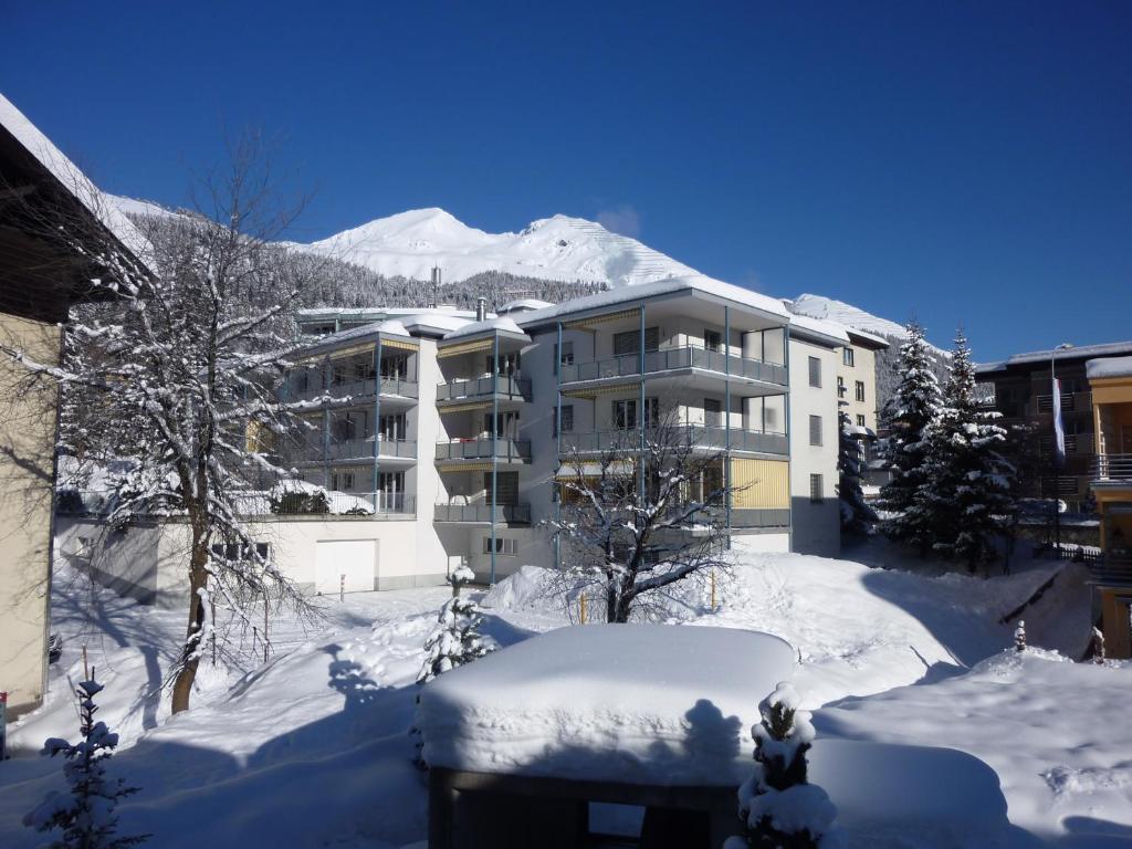 ein schneebedecktes Wohnhaus mit einem Berg im Hintergrund in der Unterkunft Valbella in Davos