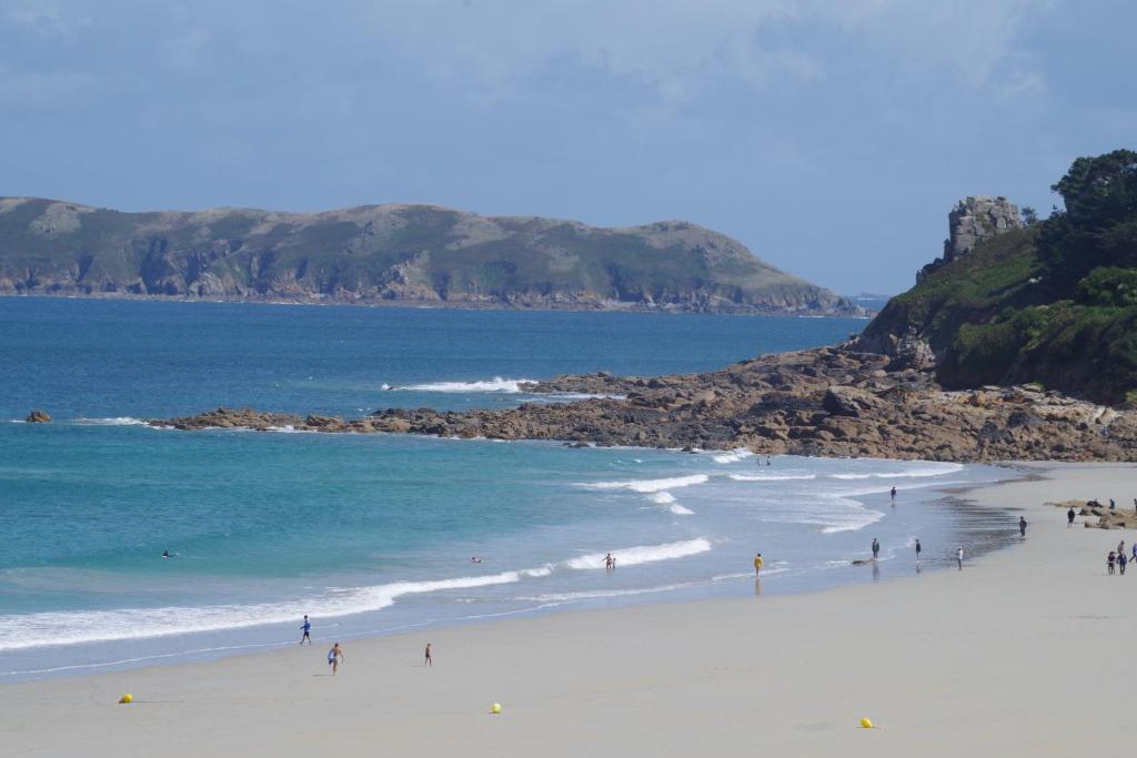 un grupo de personas en una playa cerca del océano en Le Ker Bleu, en Perros-Guirec