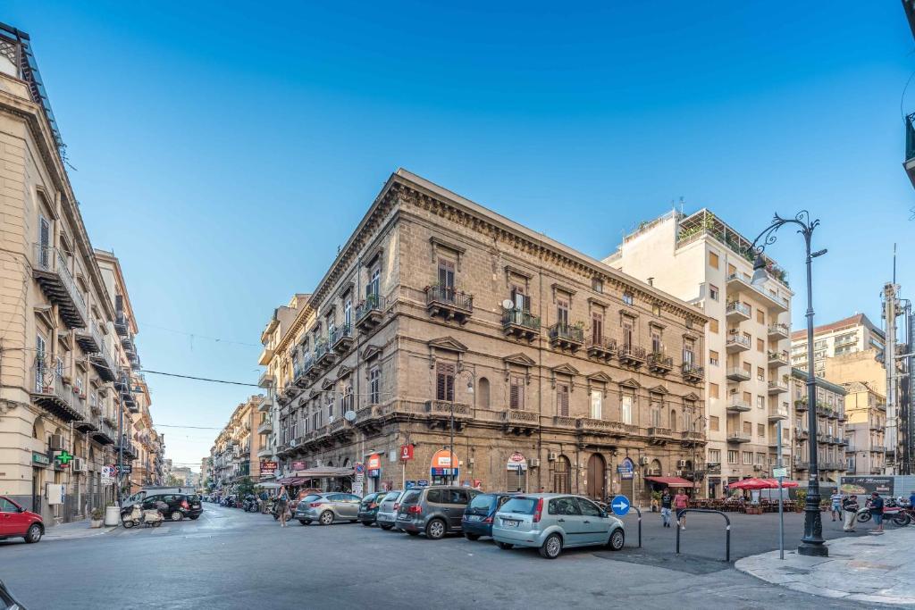una strada cittadina con auto parcheggiate di fronte a un edificio di Palazzo Benso a Palermo