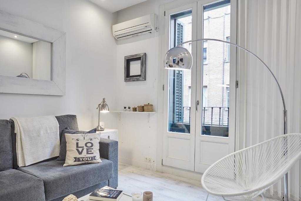 een woonkamer met een grijze bank en een raam bij LEEWAYS LOFT I in HORTALEZA in Madrid