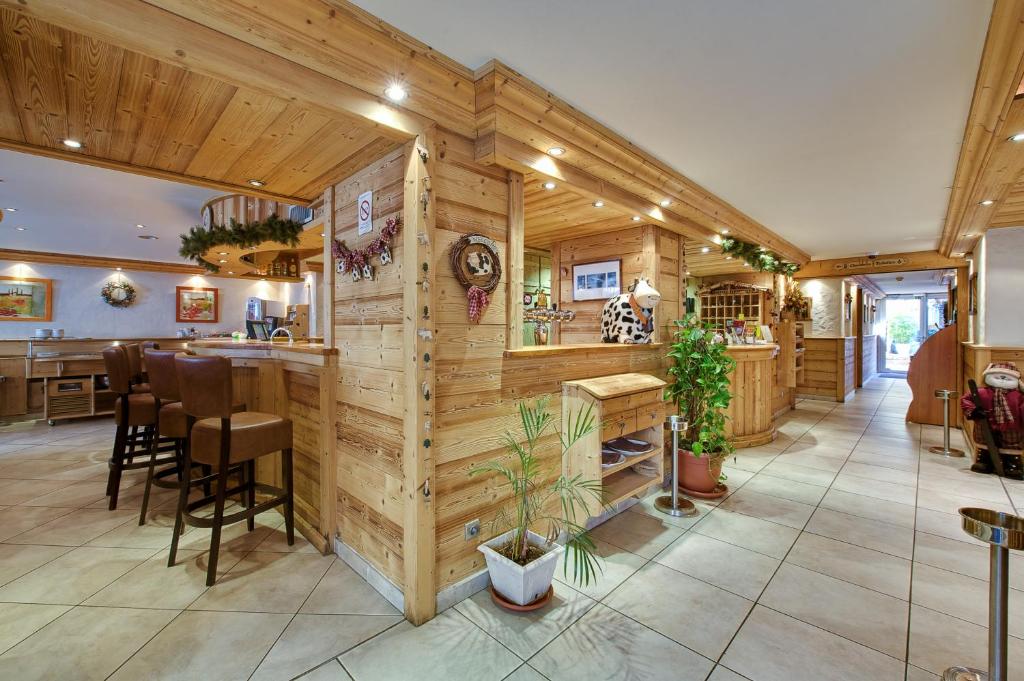 a kitchen with wooden walls and a bar with stools at Hotel Du Commerce in Thônes