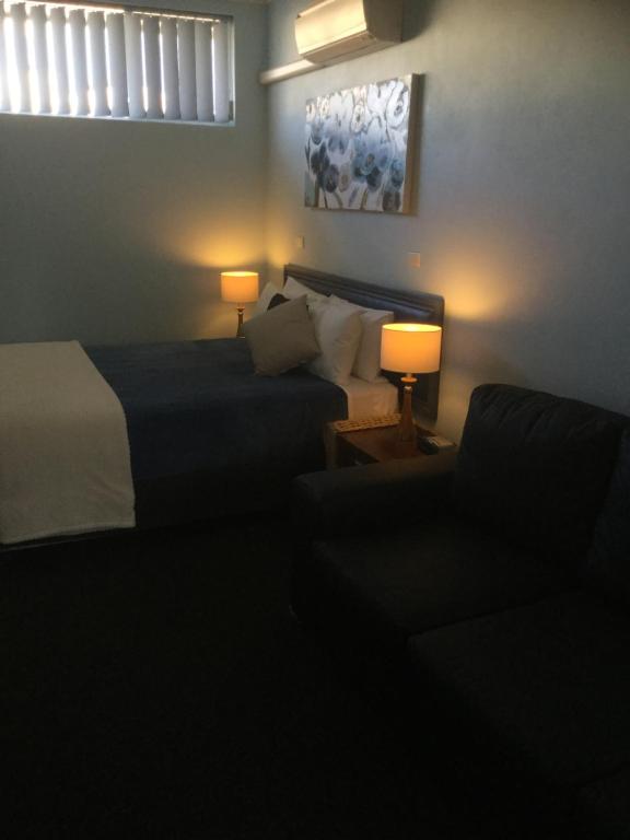 a bedroom with two beds and a couch and two lamps at Tall Timbers Motel in Dungog