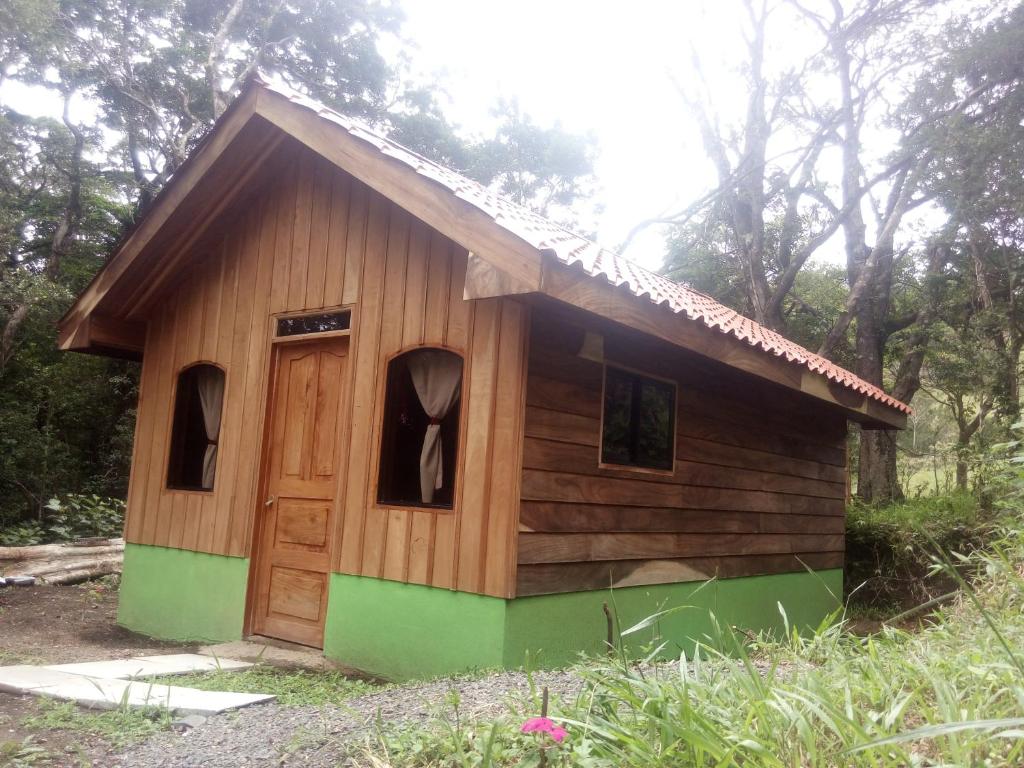 uma pequena casa de madeira com uma porta num campo em Monteverde Romantic Cottage em Monteverde