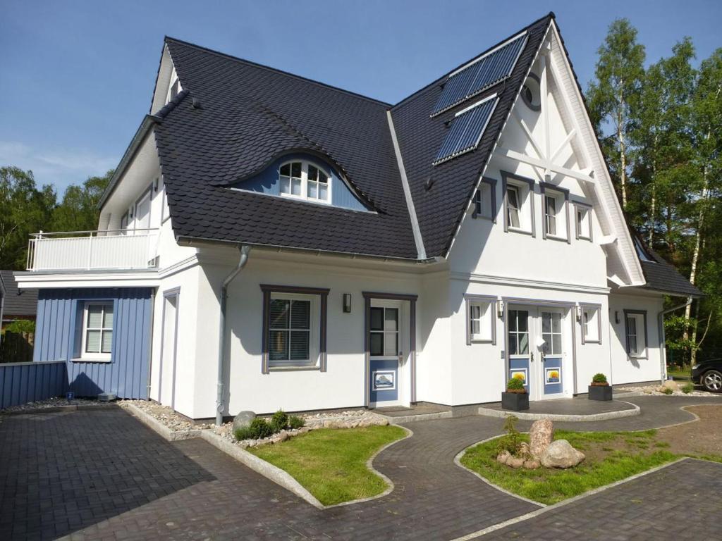 uma casa branca com um telhado preto em Lavendelblume - 4 Sterne inklusive Power WLAN - Wäschepaket - BikeBox - Parkplatz # Bestpreisgarantie # em Zingst